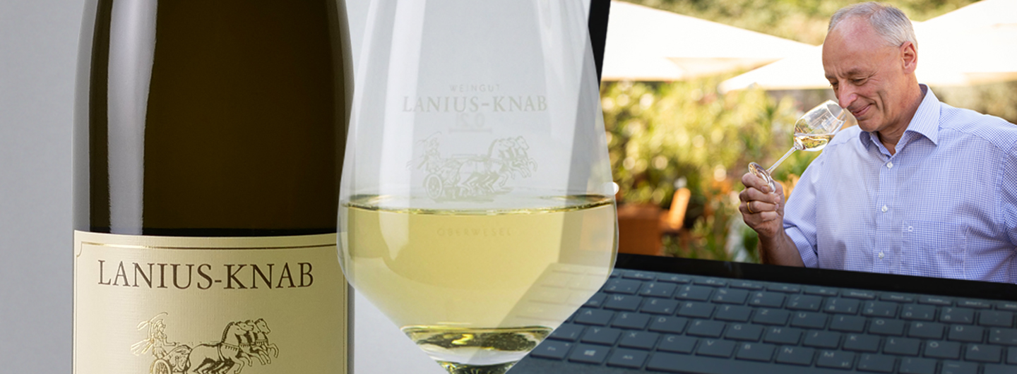 Weinflasche und Glas vor dem Laptop. Probieren Sie unsere Weine mit Jörg Lanius.