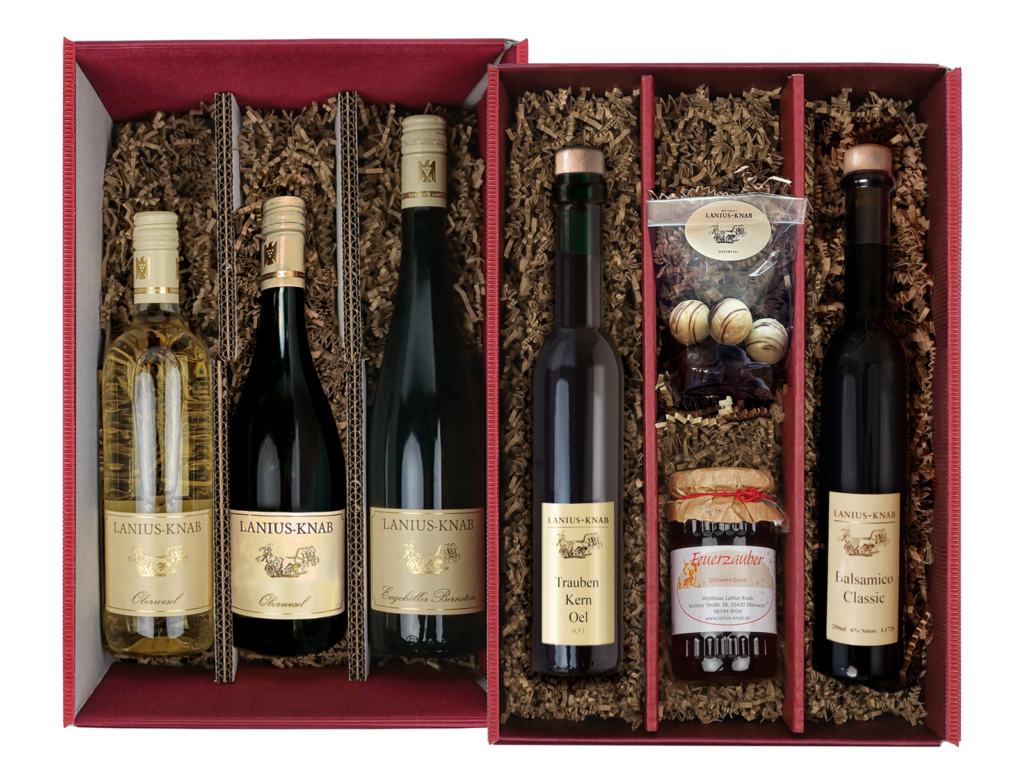 Großer roter Geschenkkarton (2teilig), 3 Weinflaschen im unteren Teil, oben eine dunkle Flasche gefüllt mit Traubenkernöl, eine Flasche gefüllt mit Balsamico, 1 Tüte mit hellen weißen und dunklen Pralinen und ein Glas Glühweingelee