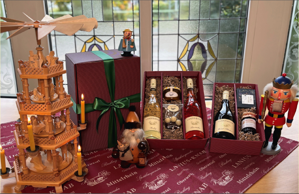 dunkelrote Geschenkpaket in verschiedenen Größen gefüllt mit Weinflaschen und andern Spezialitäten