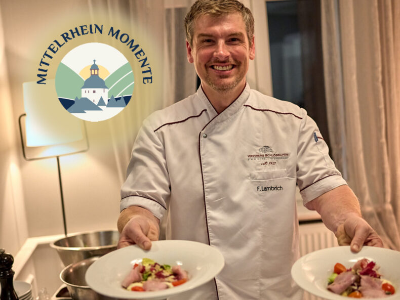 Koch in Kochjacke hält zwei gefüllte Teller.